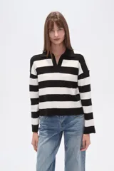 Sweater de tejido de punto, holgado, con rayas horizontales anchas en blanco y negro. Presenta cuello polo con escote en V y mangas largas.