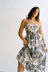 Vestido midi con breteles finos, escote cuadrado y espalda fruncida. Presenta un estampado de tigres, elefantes y vegetación en tonos azules sobre fondo blanco.