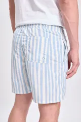 Short de baño celeste con rayas verticales blancas con efecto acuarela, cintura elástica y cordón ajustable.