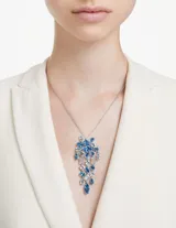 Colgante con cadena plateada y dije con forma de cascada de cristales facetados en tonos azules y blancos. El engaste está bañado en rodio.