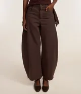 Pantalón barrel de cintura alta color marrón, confeccionado en sarga de algodón certificado BCI, con trabillas en la cintura, cierre tradicional, bolsillos convencionales y bolsillo reloj.