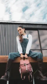 Mochila verde militar de nylon con tapa y broche metálico. Tiene apertura superior con cierre marinero, bolsillos internos, bolsillo con cierre metálico al frente y laterales. Incluye asas rígidas de mano y correas regulables para colgar en la espalda.