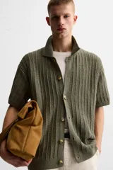 Camisa verde militar de punto con estructura abierta, corte regular fit, cuello solapa, manga corta y cierre frontal con botones.