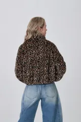 Campera corta de tejido peluche (corderito) con cierre frontal y cuello camisero. Presenta un estampado animal print de cebra o tigre en tonos marrón claro y negro.