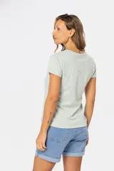 Remera color beige con estampado de aves en tonos celeste, lila y dorado.