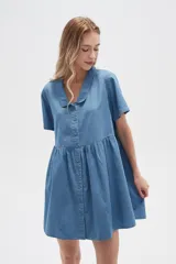 Vestido corto camisero de denim celeste, con cuello camisero, mangas cortas y falda acampanada con botones frontales.