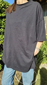 Remera negra de algodón, corte amplio, cuello redondo y mangas cortas.