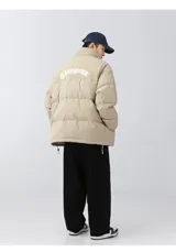 Campera puffer color nude (beige claro) con diseño acolchado. La parte superior de los hombros y el cuello son de pana acanalada. Presenta un bordado en la espalda con la palabra "Chingona" en tipografía gótica blanca. Posee tiras regulables en la cintura.