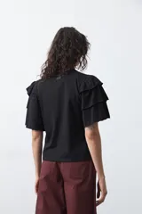 Remera negra de algodón con cuello redondo y mangas cortas con volados en capas.