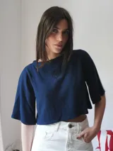 Top color beige de tejido de punto, con mangas cortas y cuello redondo. Presenta un bordado del escudo en la parte delantera.