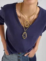 Collar dorado de doble cadena con dijes colgantes de formas geométricas irregulares.