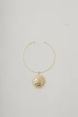 Collar corto dorado con dije grande en forma de sol con detalles plateados.