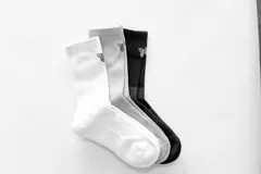 Pack de tres pares de medias de caña alta, una blanca, una gris y una negra, con logo en el tobillo.