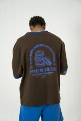 Remera oversize marrón con cuello y mangas con ribete azul. Estampado en la espalda con diseño de alfajores y texto en azul.