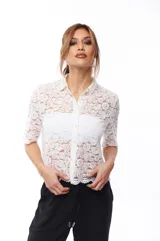 Camisa blanca de encaje con cuello clásico, cierre frontal con botones y mangas cortas.
