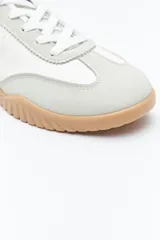 Zapatilla urbana de mujer con silueta retro, combinando paneles de gamuza marrón oscuro y material color crema en el cuerpo. Presenta detalles en color bordó en el talón y cordones beige. La suela es robusta de color marrón claro con relieve.