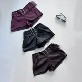 Short de cuero sintético color borgoña con cinturón negro con hebilla metálica.
