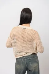 Sweater calado color beige de hilo con escote en V, mangas largas y silueta relaxed.