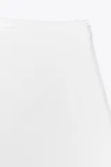 Bermuda negra de tiro alto con bolsillos delanteros de vivo y cierre lateral con cremallera oculta en costura.