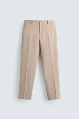 Pantalón de vestir color beige, corte slim fit, confeccionado en tejido con viscosa. Cuenta con bolsillos frontales y traseros de doble vivo con botón. Cierre frontal con cremallera y botón.