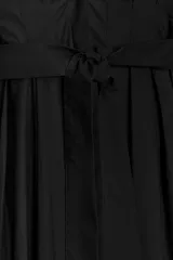 Vestido midi negro de algodón, con escote pico pronunciado, manga larga con puños y detalle de pliegues en el torso. Incluye un cinturón ajustable del mismo tejido anudado a la cintura.