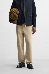 Pantalón color arena de corte recto, confeccionado en tejido de algodón con estructura canvas. Cuenta con cintura ajustable con trabillas laterales, bolsillos frontales y traseros de vivo. Cierre frontal con cremallera y botón.