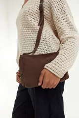 Bandolera marrón de gamuza con correa ajustable del mismo material.