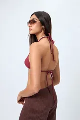 Top de bikini negro confeccionado en tejido con textura, de diseño triangular y detalle de aros cuadrados en los breteles. Se ajusta en cuello y espalda con lazos finos.