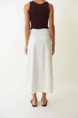 Falda pareo blanca de corte asimétrico, con lazo ajustable en la cintura y tajo frontal.