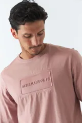 Remera de hombre de manga larga color rosa con cuello redondo y logo bordado en relieve en el pecho.