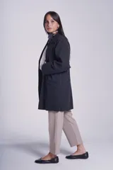 Tapado gris oscuro de corte oversize, con solapa clásica, hombros caídos, cierre con un botón central y bolsillos laterales funcionales.