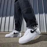 Zapatillas Nike Air Force 1 color beige con detalles en crema, suela blanca y base color caramelo.