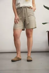 Short de vestir color beige claro, tiro alto, con pliegues frontales y lazo para ajustar la cintura.