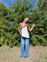 Musculosa blanca con escote en V y detalles de encaje negro en el escote y el dobladillo. Tiene tirantes finos.