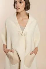 Chal de lana fina sin teñir, con calce en hombros, abrochadura con alamar de fieltro, bolsillos de cuero y terminación con flecos. Diseño exclusivo de Don Baez, hecho en Uruguay.