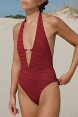 Traje de baño enterizo marrón acanalado, con escote profundo en V y abertura en el centro unida por una argolla dorada.