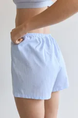 Shorts de pijama celestes con cintura elástica y cordón ajustable. Uno de los lados es de tela a rayas verticales blancas y celestes.
