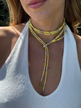 Collar amarillo con tres tiras de cuero sintético y cuentas plateadas.