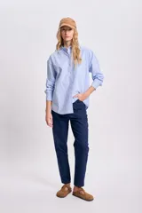 Camisa celeste con rayas verticales blancas, de corte holgado, manga larga y cuello clásico.