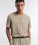 Camisa boxy masculina de viscosa color beige, con mangas cortas, cuello camisero y abotonadura frontal.