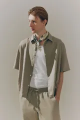 Camisa color beige de manga corta con cuello inglés y tapeta con botones. Corte holgado.
