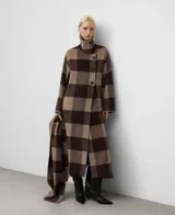 Abrigo largo de corte recto confeccionado en mezcla de lana merino con diseño de cuadros en tonos arena y marrón. Presenta cuello chimenea con cierre de botones, manga larga, delantero cruzado con botonadura y aberturas laterales.
