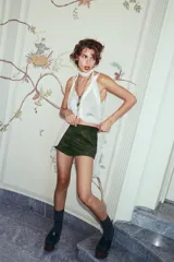 Shorts mini color verde militar, de tiro medio con trabillas, bolsillos delanteros y traseros. Cierre frontal con cremallera, botón interior y gancho metálico.