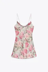 Vestido corto con estampado floral en tonos rosa y verde, escote fluido, tirantes finos y volantes en el lateral.