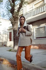 Buzo de lana color beige con cuello alto con cierre y aplique de corderito en el cuello. De mangas rectas y corte amplio.