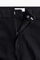 Jean de denim negro con leve stretch, corte ajustado de cintura a cadera y acampanado desde la rodilla al bajo. Es de tiro alto con cierre, botón oculto y corchete. Tiene bolsillos traseros decorativos y pliegues delanteros y traseros.