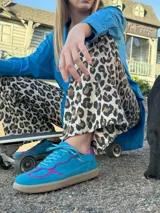 Championes de cuero vacuno color celeste con detalles en fucsia, suela color caramelo y cordones celestes.