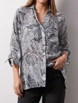Camisa de mujer estampada con hojas en blanco y negro, cuello con solapa, abertura central con botones, bolsillos aplicados en el delantero y mangas largas con lazo.