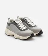 Championes dad sneaker grises con recortes en cuero sintético, cordones blancos y suela chunky de goma color crema.