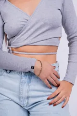 Remera corta gris de punto con escote cruzado y mangas largas.